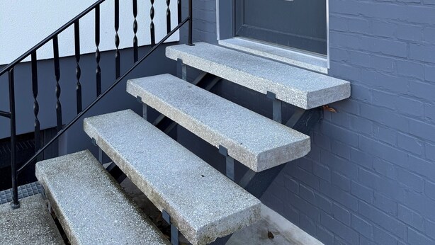 A modern exterior with a grey door, a number '29' sign, and a small set of stone steps leading to a glass door. - Renovated EFH, Schwerin lake district. Nature and culture within easy reach (Leezen)