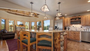 A spacious kitchen with wooden cabinets, a stone island, and pendant lighting. - 144 Rainbow - Fairways at Pole Creek 6 beds, private outdoor HT, heated garage (Tabernash)