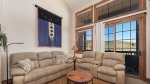 Una sala de estar con un sofá modular, una mesa de centro y un ventanal con vistas a un paisaje montañoso.