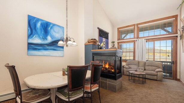 Una sala de estar con chimenea, una mesa de comedor con sillas, un sofá y un cuadro grande en la pared.