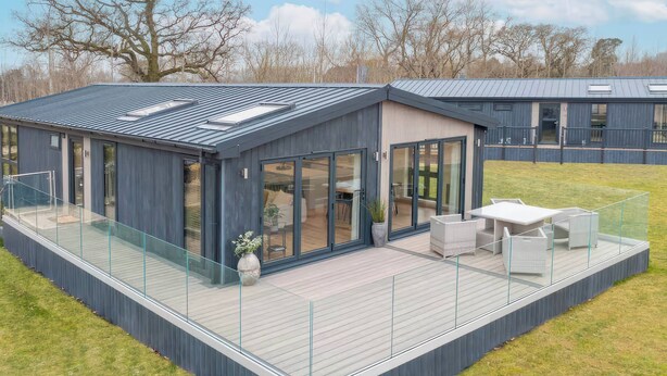 Ein modernes Haus mit Terrasse, großen Fenstern und einer Flachdach.