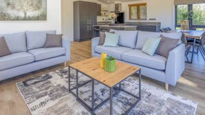 Ein modernes Wohnzimmer mit zwei Sofas, einem Couchtisch und einer Küche im Hintergrund.