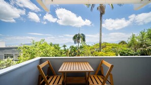 A balcony with a wooden table and chairs, overlooking a lush landscape with palm trees and a clear sky. - Apart With sea View 400m From the Beach Cbo0103 (Florianópolis)
