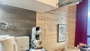 Een keuken met een koffiezetapparaat, een broodrooster en een ingelijst foto aan de muur.