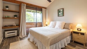 A bedroom with a bed, bedside tables, a ceiling fan, a window with curtains, a shelf with plants, and a wall-mounted picture. - Charming Renovated Condo w/Loft & Golf Views near Ritz-Carlton Turtle Bay (Kahuku)