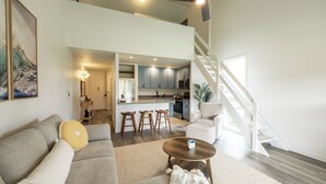 A spacious living area with a sofa, a coffee table, and a staircase leading to an upper level. - Charming Renovated Condo w/Loft & Golf Views near Ritz-Carlton Turtle Bay (Kahuku)