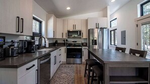 Een moderne keuken met roestvrijstalen apparatuur, een centraal kookeiland en grote ramen.