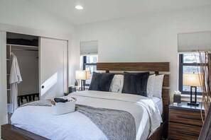 Ein ordentlich eingerichtetes Schlafzimmer mit Bett, Nachttischen, einem Fenster mit Jalousien.