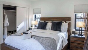 Een keurig opgemaakt slaapkamer met een bed, nachtkastjes en een raam met zonwering.