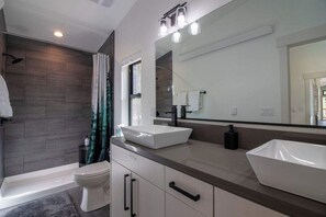Ein modernes Badezimmer mit Badewanne, zwei Waschbecken und einem großen Spiegel.