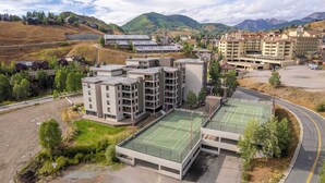 A modern hotel complex with multiple buildings, a tennis court, and a parking area. - Plaza 536 | Shuttle to Crested Butte Lifts | Hot Tubs+Sauna | 2BR Sleeps 6 (Crested Butte)