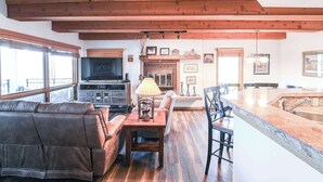 A spacious living area with a sofa, a dining table, and a kitchen island. - Plaza 536 | Shuttle to Crested Butte Lifts | Hot Tubs+Sauna | 2BR Sleeps 6 (Crested Butte)