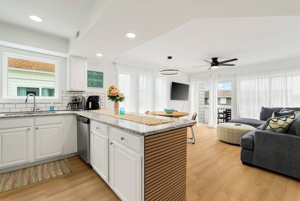 A modern kitchen with white cabinetry, a central island, and a dining area with a round table.