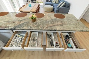 Eine Küche mit Marmorarbeitsplatte, mehreren Schubladen für Utensilien und einem Essbereich mit Tisch und Stühlen.