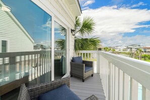 A balcony with wicker furniture and a glass door leading to a pool area. - Beach Buddies 2 is 3 bed/2 bath with pool (North Myrtle Beach)