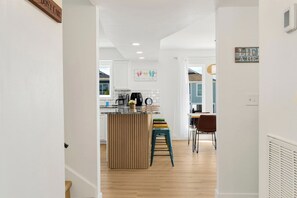 Eine moderne Küche mit Kochinsel, Barhocker und einem Essbereich mit Stühlen.