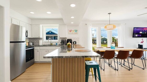 A modern kitchen with white cabinets, a stainless steel refrigerator, and a wooden island. - Beach Buddies 2 w/pool (North Myrtle Beach)