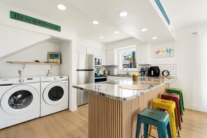 Ett modernt kök med inbyggda vitvaror, en köksö och en skylt med texten ”Strandhus”.