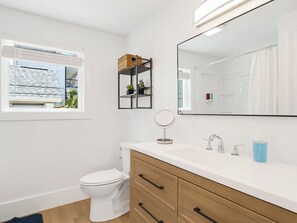 Ein modernes Badezimmer mit Toilette, Waschtisch mit Spiegel und Fenster mit Jalousien.