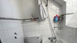 A bathroom with a bathtub, toilet, and shower. - Room-angelos Home in Bermondsey (London)