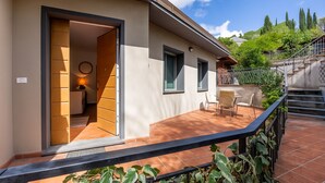 Un edificio moderno con un patio que cuenta con una mesa, sillas, una escalera y vistas del paisaje circundante.