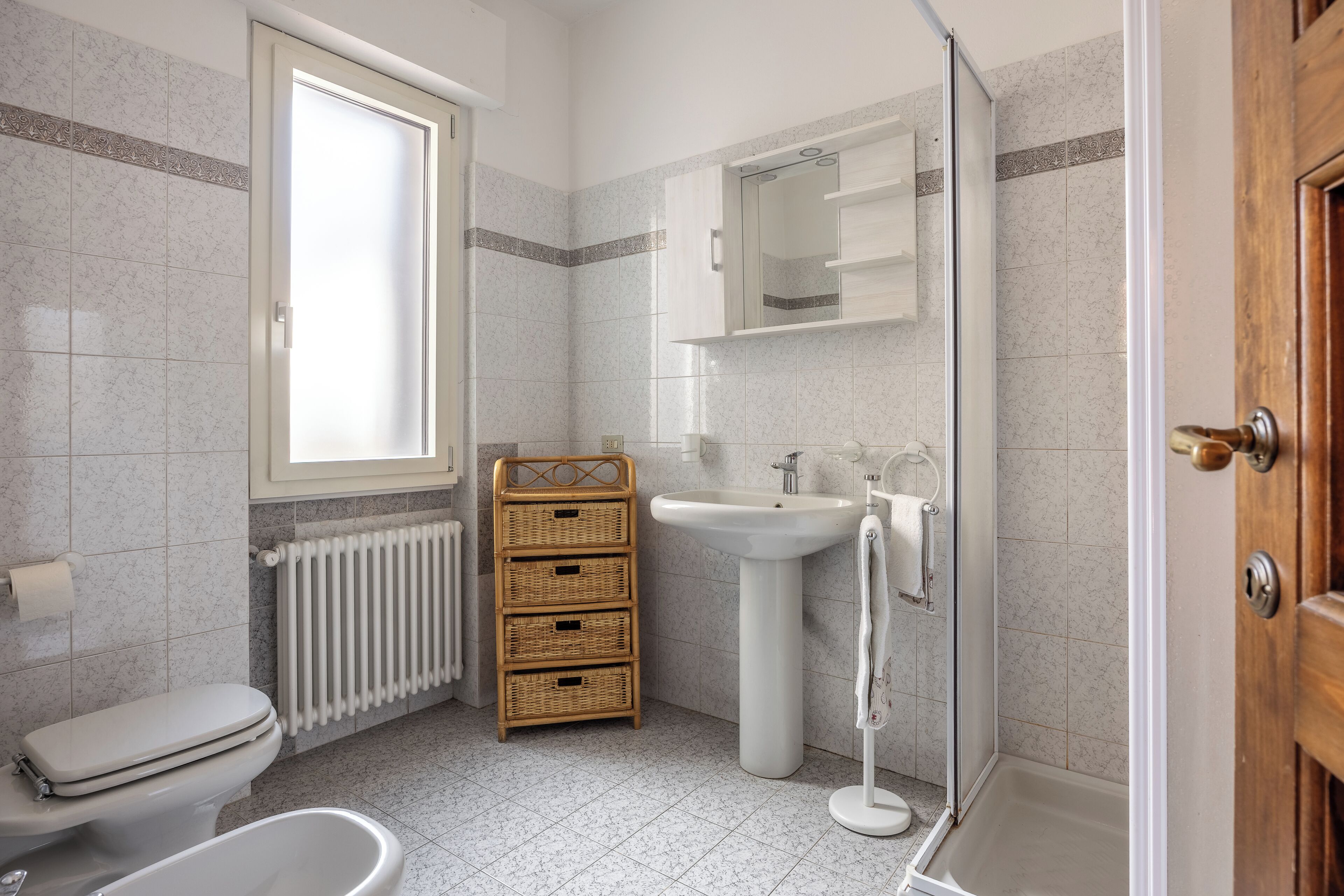A bathroom with a toilet, a sink, a shower, and a window.