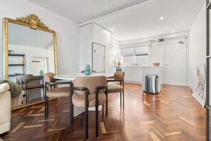 A modern living room with a dining area, a large mirror, and a kitchen in the background. - Elegance in Darling Point (Darling Point)
