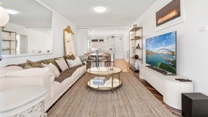 A modern living room with a sofa, coffee table, TV, and kitchen in the background. - Elegance in Darling Point (Darling Point)