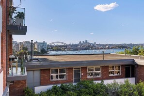 A building with a rooftop terrace overlooking a harbor with boats and a city skyline, including a prominent bridge. - Elegance in Darling Point (Darling Point)