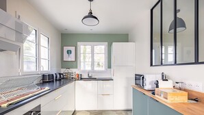 Una cocina moderna con armarios blancos, encimera negra y suelo con patrón hexagonal.