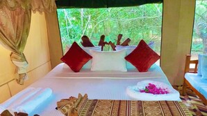 Ein stilvoll eingerichteter Raum mit einem Bett, Kissen, einem dekorativen Holzobjekt und einem Tisch mit Blumen.