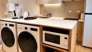 A compact kitchen with a washing machine, microwave, coffee maker, and a sink. - Mullaejung (Seoul)