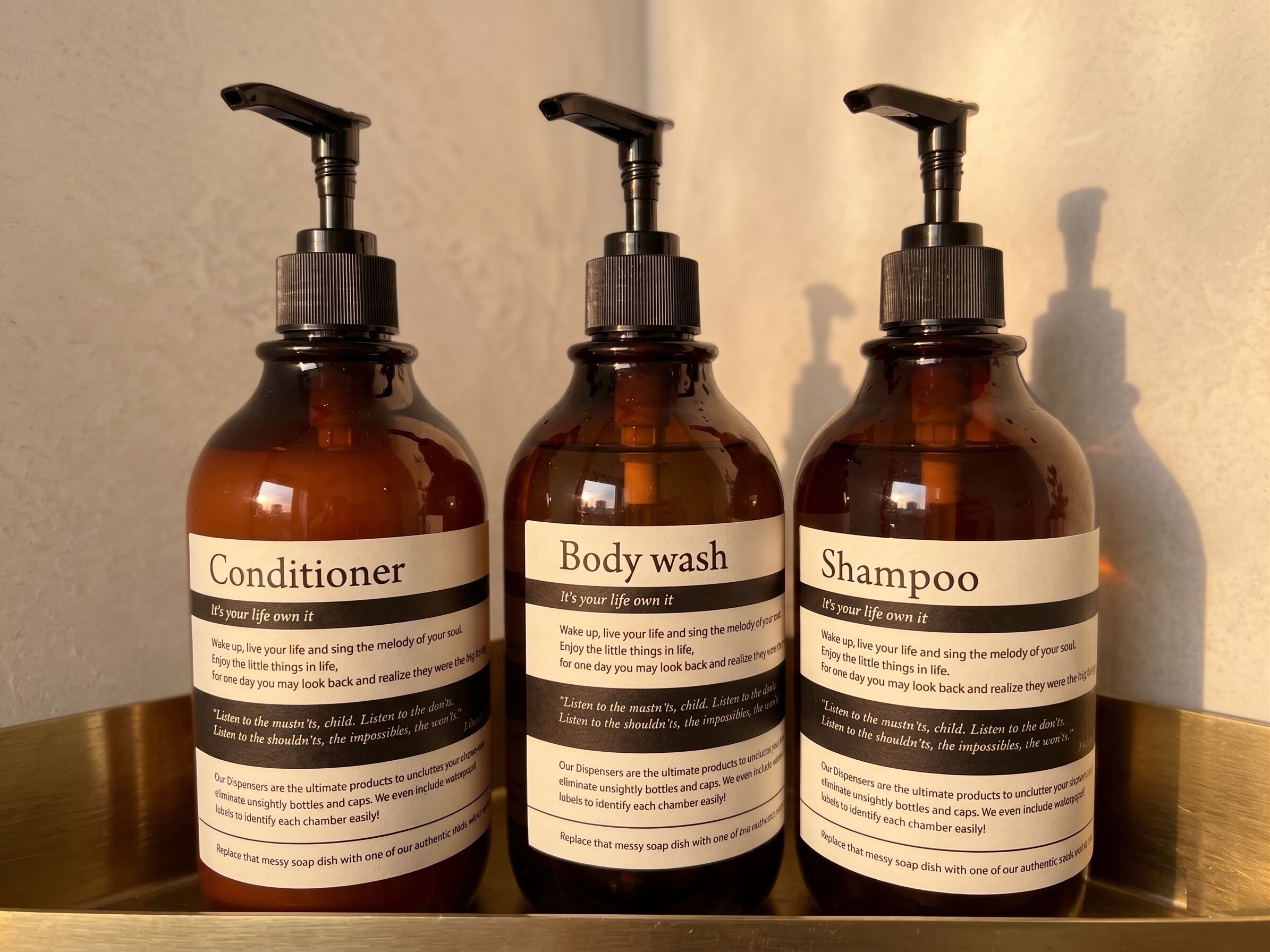 Three bottles of liquid soap with pumps, labeled as conditioner, body wash, and shampoo.