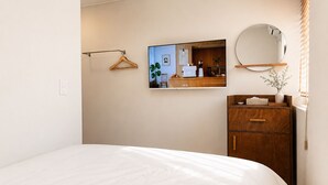 A bedroom with a bed, a dresser, a mirror, and a wall-mounted TV. - Mullaejung (Seoul)