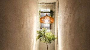 A narrow stairway with a potted tree, a hanging light fixture, and a window with barred glass. - Mullaejung (Seoul)