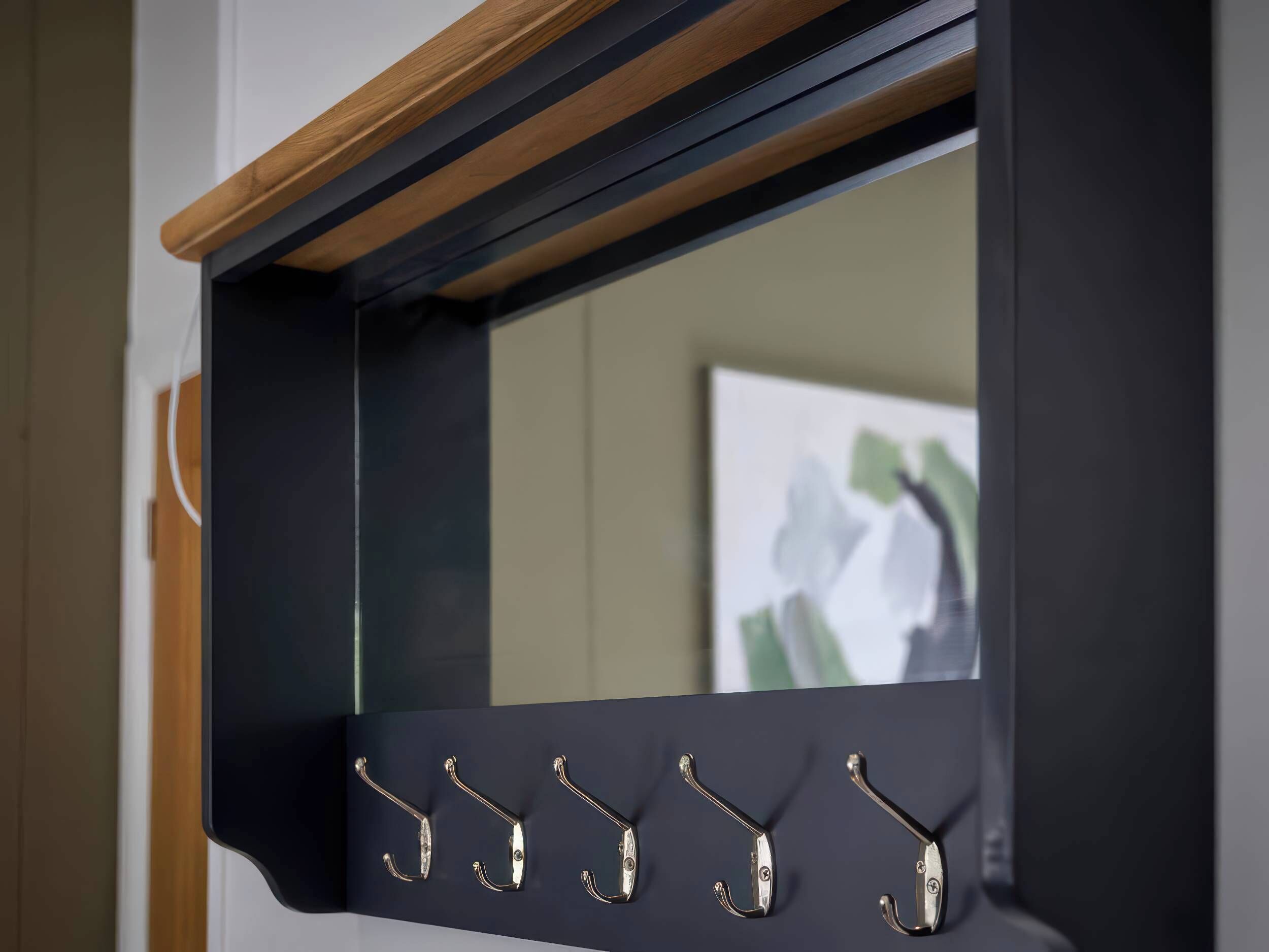 A black wall-mounted mirror with five hooks.