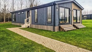 Ein modernes Haus mit überdachter Veranda, Kiesweg und Rasengrundstück.