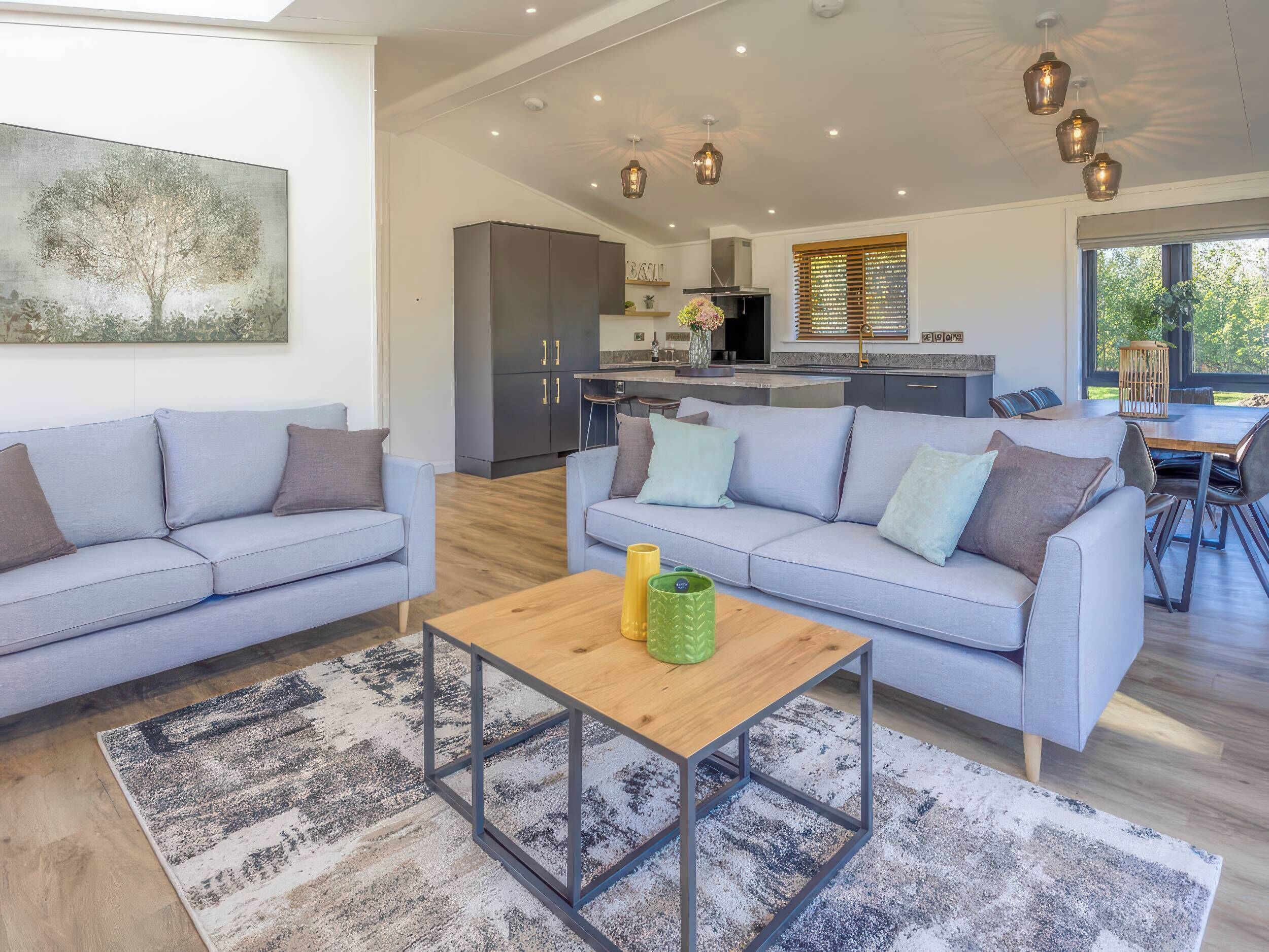 A modern living room with a grey sofa, a wooden coffee table, and a patterned rug.