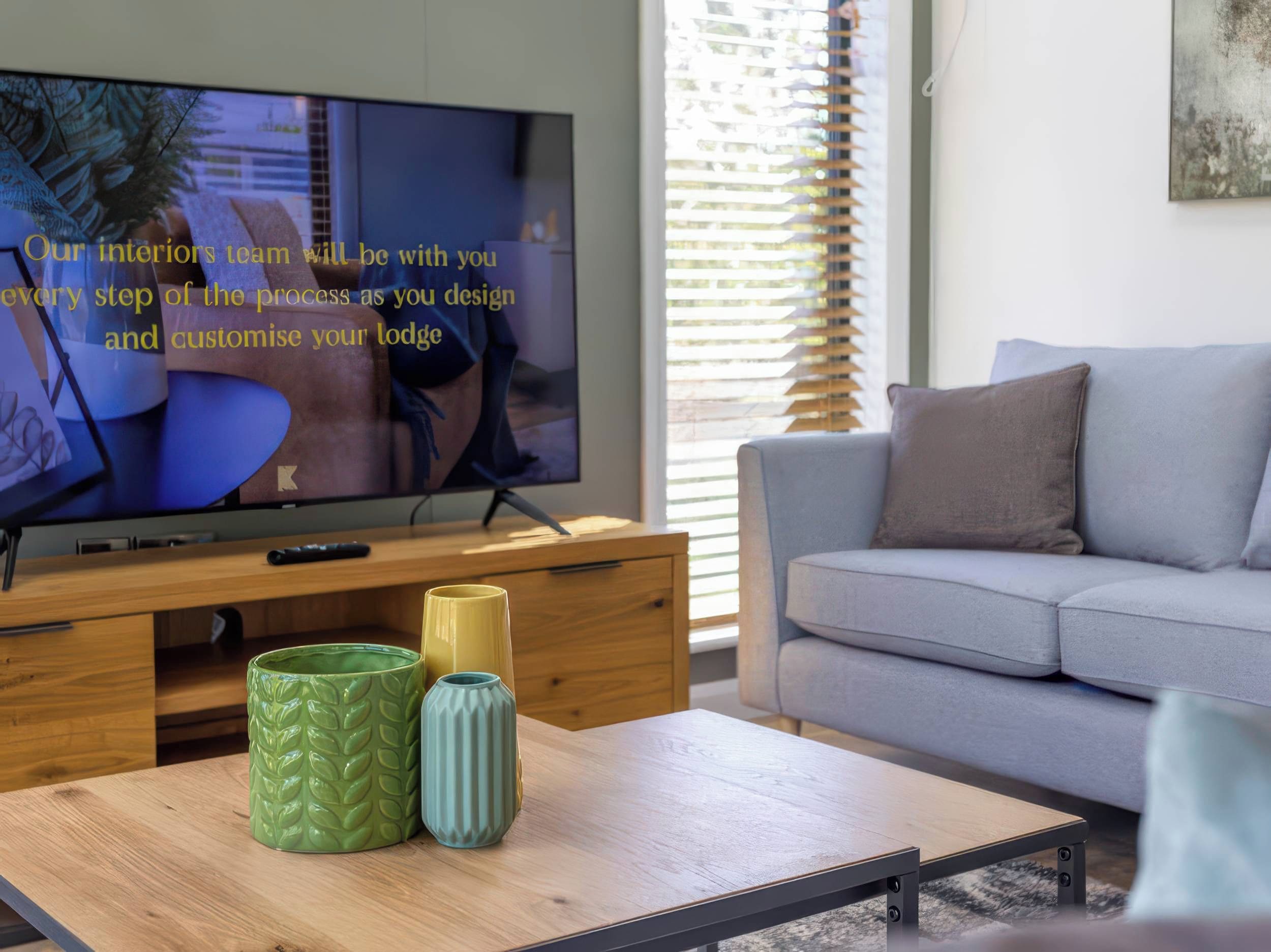 A modern living room with a television, a sofa, and decorative vases on a coffee table.