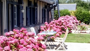 A building with a covered outdoor seating area, a staircase, and a garden with pink flowers. - Blue Azur Guest Room with Shared Terrace & Garden, Wi-Fi (Honfleur)