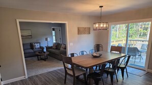 A dining area with a wooden table and chairs, a bowl of fruit, and a view of the outdoors through a sliding glass door. - New Home with Game Room and Nature Trails in Port Huron (Port Huron)