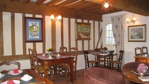 A dining room with wooden beams, a table set for four, and a sofa.