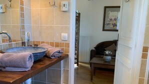 Ein Badezimmer mit einem großen Waschbecken, Handtüchern, einem Toilettenpapierhalter und einer Duschkabine.