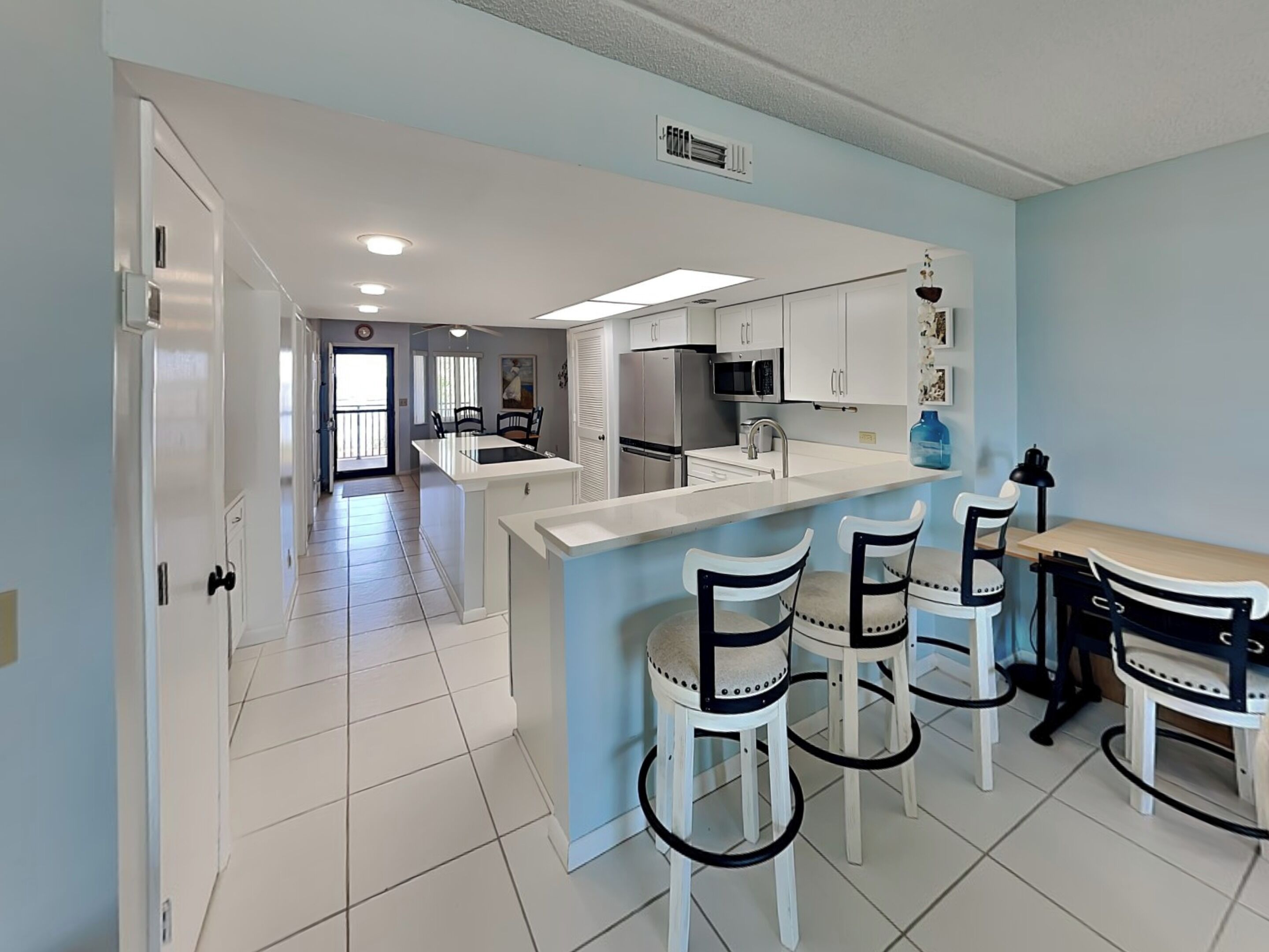 A modern kitchen with white cabinets, a central island, and bar stools.