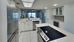 A modern kitchen with white cabinets, a black stove, and a view to the outside. - Windjammer 215 | Balcony Views + Resort Amenities (St. Augustine)