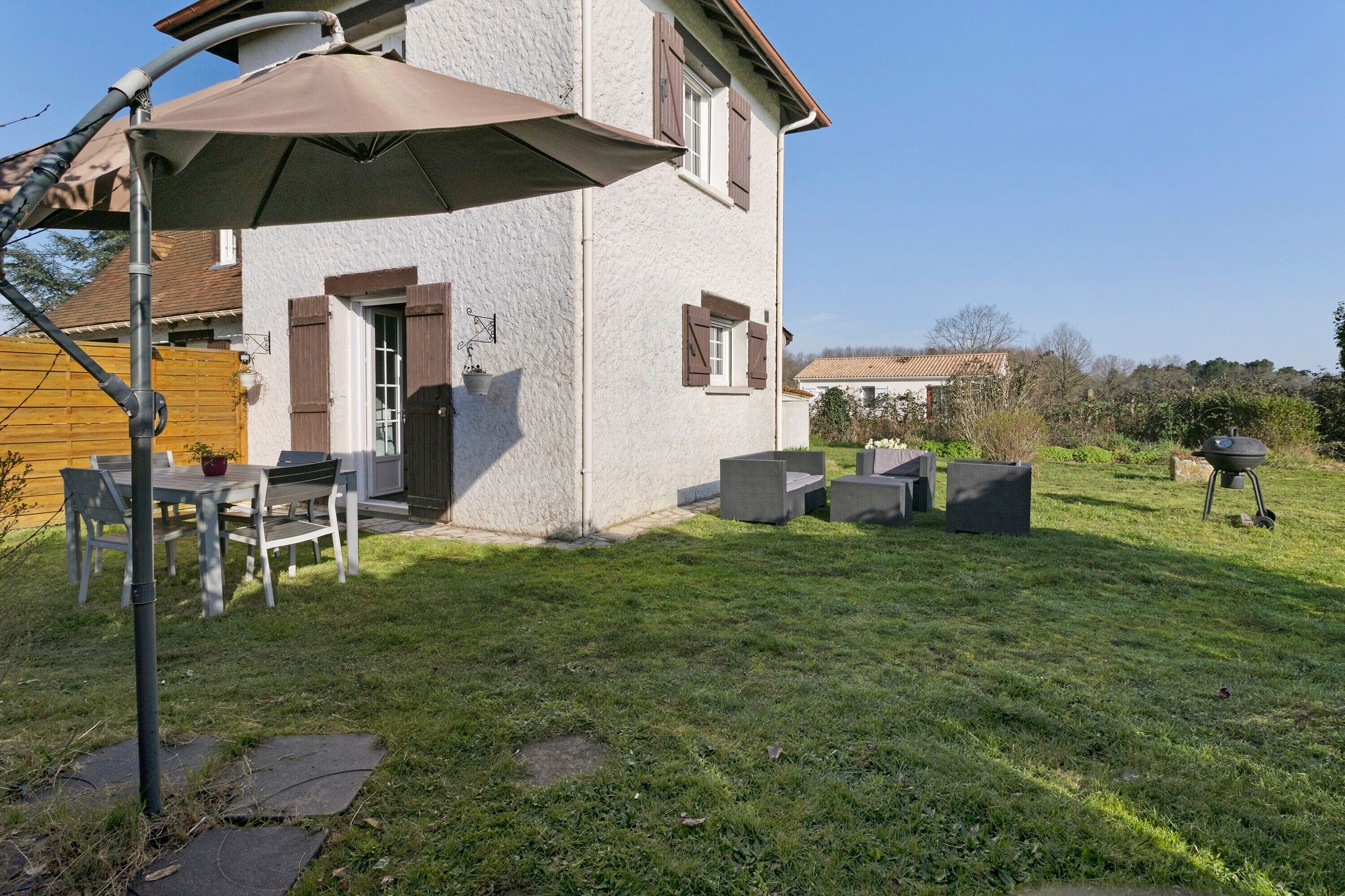 Een huis met een terras, buitenmeubels en een barbecue.