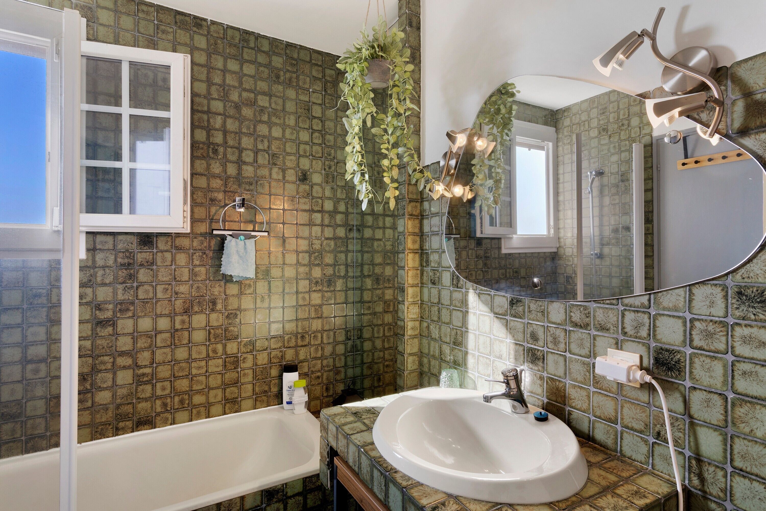 A bathroom with a bathtub, a sink, a mirror, and a shower.