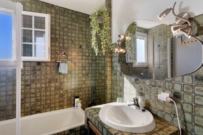 Une salle de bain avec une baignoire, un lavabo, un miroir et une douche.