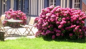 A building with a striped facade, outdoor seating, and a large bush of pink flowers. - “Romantic Suite” Guest Room with Shared Terrace & Garden, Wi-Fi (Honfleur)
