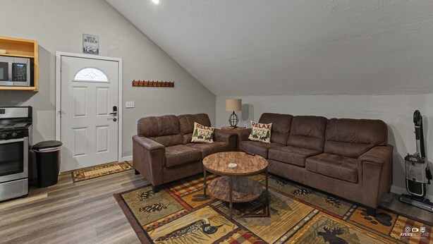 Un salon avec deux canapés en cuir marron, une table basse en bois, un tapis à motifs, un four à micro-ondes, une poubelle et une porte avec une pancarte.